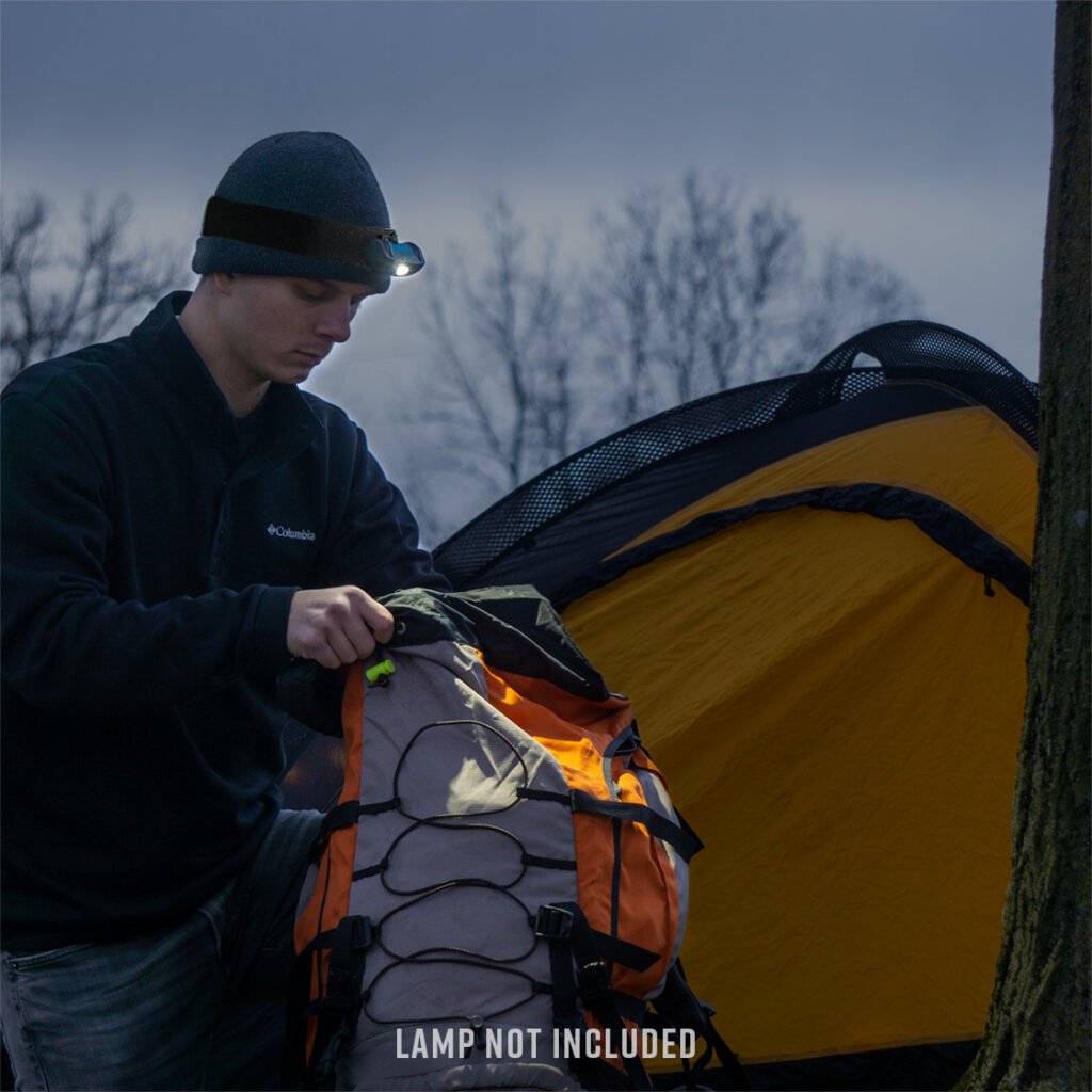 Man using Head Light to see inside of his backpack at night while camping.
