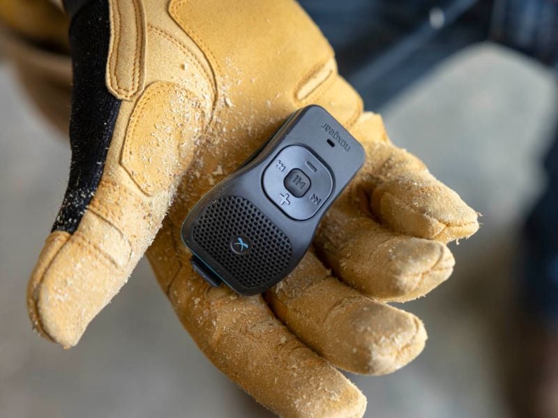 A Noxgear 39g speaker sits in a hand wearing a leather work glove. The 39g is the best jobsite Bluetooth speaker with its lightweight, portable design.