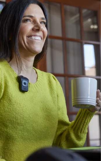 Photo of a smiling woman holding a cup of coffee while wearing a 39g on her shirt.