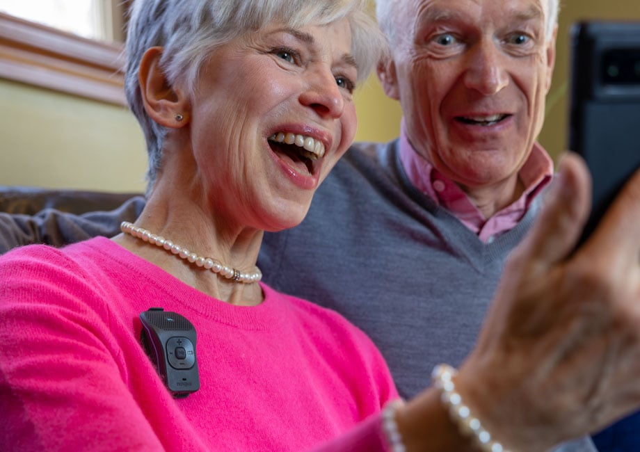 An older man and woman looking at a phone, the woman is wearing a 39g.
