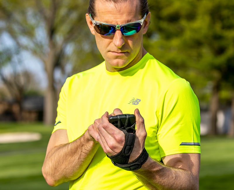 Man wearing a neon yellow shirt using the Noxgear Phone Holder.