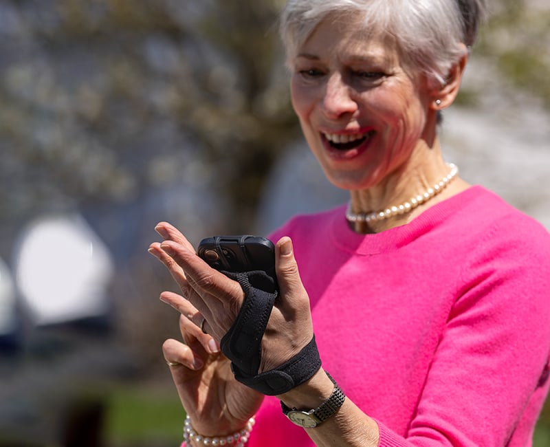 Woman wearing a pink shirt using the Noxgear Phone Holder.