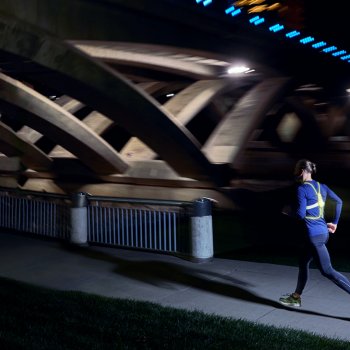 Man running at night wearing a Tracer 2, bridge in the background.