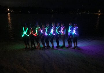 Ten runners in multi-colored noxgear pose on the beach
